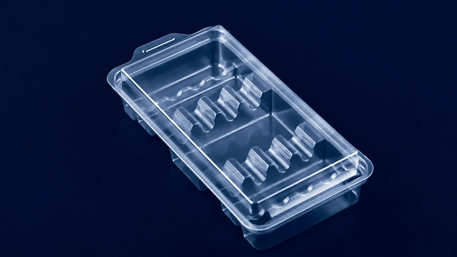 Clear thermoformed medical tray with shaped instrument pockets on a dark blue background